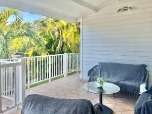 a porch with a couch and a table and palm trees at Villa martinique in Sainte-Luce