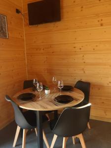 a wooden table with chairs and wine glasses on it at Domki na Stodoliskach in Kasinka Mala