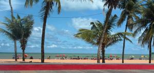 a beach with palm trees and people on the beach at Luxor Tambaú Beach Paradise in João Pessoa