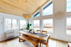a dining room with a wooden table and some windows at The Kiwanda Surf House in Pacific City