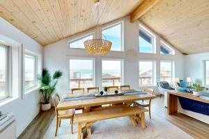 a dining room with a table and chairs and windows at The Kiwanda Surf House in Pacific City