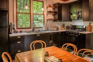 a kitchen with black cabinets and a wooden table at The Cottage at Forest Inn in Douglas