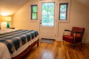 a bedroom with a bed and a chair and a door at The Cottage at Forest Inn in Douglas