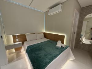 a small bedroom with a bed with a green blanket at Apartamento com suíte e sala com ar-condicionado in Barreiras