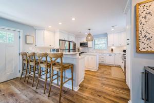 a kitchen with white cabinets and a bar with stools at Beach Blessing in Southern Shores