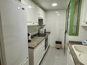 a white kitchen with a sink and a refrigerator at Exclusive flat in Patacona Beach in Valencia +15 photos
