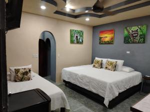1 dormitorio con 2 camas y cuadros en las paredes en Casa veranera, en Quepos