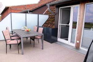 einen Holztisch und Stühle auf einem Balkon mit Glastür in der Unterkunft Sonnenblume in Fehmarn + 8 Fotos