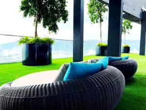 Sofá de mimbre con almohadas azules en la hierba en Perfect for Groups! 2BR with 5 Queen Beds & WiFi, en Jelutong