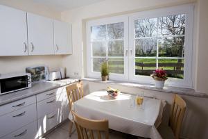 a kitchen with a table with chairs and a kitchen with windows at Kastanie in Fehmarn