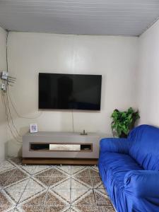 Una sala de estar con un sofá azul y un televisor de pantalla plana. en Casa para Cop 30, en Ananindeua