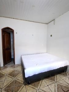 una cama en una habitación con una pared blanca en Casa para Cop 30, en Ananindeua 4 fotos más