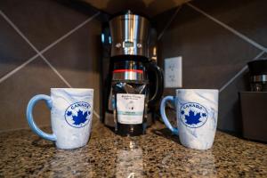 tre tazze da caffè sedute su un bancone con un frullatore di The Raven Suite at Stoneridge Mountain Resort a Canmore