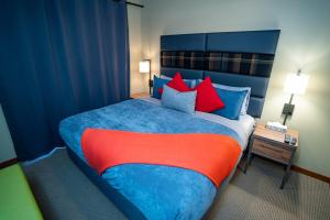 una camera da letto con un grande letto con cuscini blu e rossi di The Raven Suite at Stoneridge Mountain Resort a Canmore Altre 16 foto