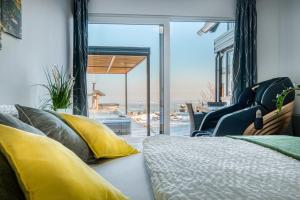 a bedroom with a bed with yellow pillows and a window at Panoramic View Cottage House - Private Wellness Retreat in Hočko Pohorje