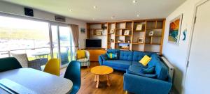 ein Wohnzimmer mit einem blauen Sofa und einem Tisch in der Unterkunft No 1 Oceans in Perranporth