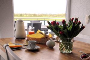 a table with a vase of flowers and a basket of food at Gänseblümchen in Fehmarn
