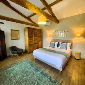 a bedroom with a large white bed and a chair at Le Chemin in Challignac +81 photos