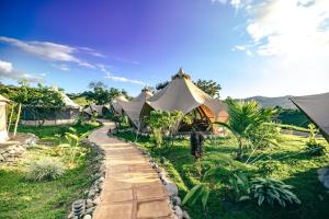a row of tents in a field with a path at Eco Luxe Glamping Nest #12 - King Bed at Holos in Barú