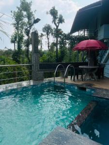 uma piscina com uma mesa e um guarda-sol em Coorg Sana Riverside em Suntikoppa
