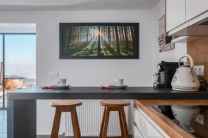 a kitchen with two stools and a picture on the wall at Panoramic View Cottage House - Private Wellness Retreat in Hočko Pohorje