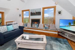 a living room with a blue couch and a tv at Heron's Cove on Salt Meadow - Pet friendly, waterfront home! in Deep Hole