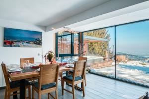 a dining room with a table and chairs and a large window at Panoramic View Cottage House - Private Wellness Retreat in Hočko Pohorje