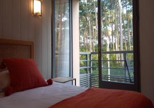 a bedroom with a bed and a large window at Les Jardins de L'Ocean - Climatisé in Biscarrosse-Plage