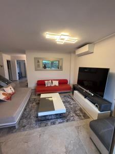 ein Wohnzimmer mit einem roten Sofa und einem Flachbildfernseher in der Unterkunft Villa Marina Cottage in Mandelieu-la-Napoule + 33 Fotos