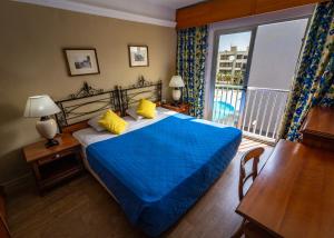 a bedroom with a blue bed and a balcony at Topaz Hotel in St Paul's Bay