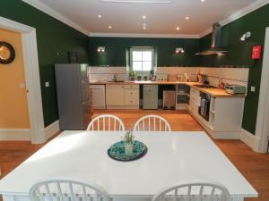 cocina con paredes verdes, mesa blanca y sillas en The Old Laundry Cottage, en Perth