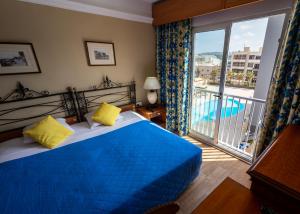 a bedroom with a bed and a balcony with a pool at Topaz Hotel in St Paul's Bay