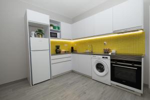 a kitchen with a white refrigerator and a washing machine at Casa Limão - Senhora da Rocha, Algarve in Porches