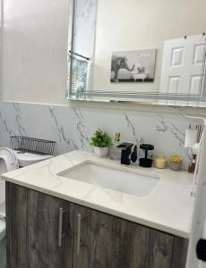 ein Badezimmer mit einem weißen Waschbecken und einem Spiegel in der Unterkunft Island Haven 5BR Home with Pool Cottage in Nassau