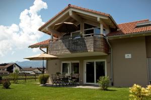 a house with a balcony with a table and umbrella at Das Alpiente - Das Urlaubshaus im Allgäu in Sonthofen