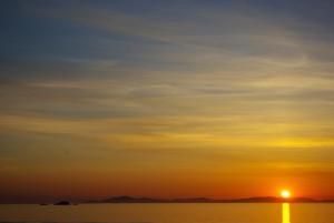 a sunset over the water with the sun in the sky at Whitewave in Monkstadt