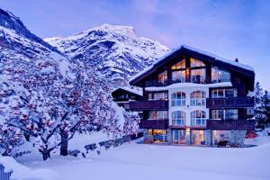 ein Haus im Schnee mit Bergen im Hintergrund in der Unterkunft Alex Lodge Private Luxury Apartments in Zermatt