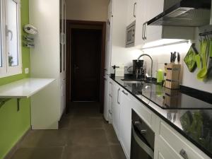 a kitchen with white cabinets and green walls at Los Jazmines in Agaete