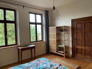 a bedroom with a bed and a table and windows at Großzügige Gutshaus-Wohnung nahe Saale und Elbe in Schwarz