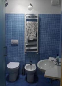 a blue tiled bathroom with a toilet and a sink at Al villino Duse in Genova
