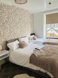 a bedroom with two beds and a patterned wall at Idan House in Llanberis