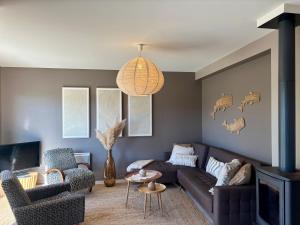 a living room with a brown couch and chairs at Le Cocon Iodé - 100m des plages-GR34-skatepark-kite-surf-voile-terrasse-jardin in Clohars-Carnoët
