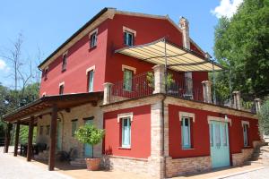Un edificio rojo con un balcón en la parte superior. en Ferienhaus Casa Sacciofa In Monte Rinaldo, en Monte Rinaldo