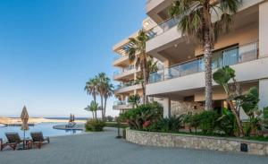 カボ・サン・ルーカスにあるOceanfront 3BR Condo at Diamante by The Agency Bajaのヤシの木とスイミングプールのあるアパートメントビル