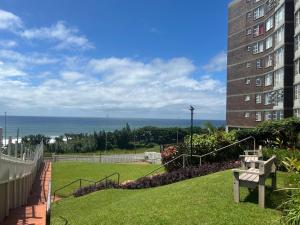 a bench sitting in the grass next to a building at Beachfront Apartment in Scottburgh