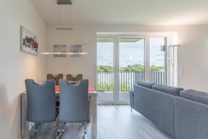 a dining room with a table and chairs and a balcony at Auszeit am Deich in Nordstrand +10 photos