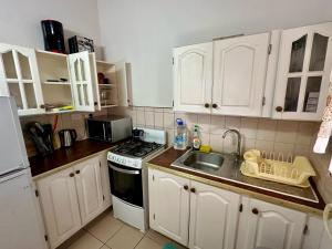 una cucina con mobili bianchi, un lavello e una stufa di OCEAN VIEW APARTMENTs a Belmont Altre 6 foto