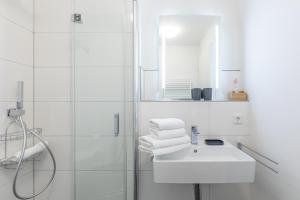 a white bathroom with a sink and a shower at Auszeit am Deich in Nordstrand