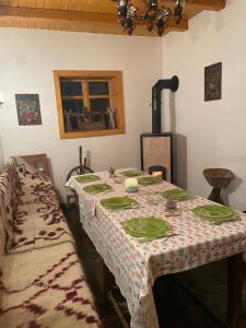 a dining room with a table with green plates on it at Sura de pe Codrisor in Leordina