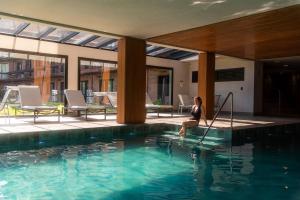 a woman sitting on the edge of a swimming pool at Hotel Alpestre in Gramado +129 photos